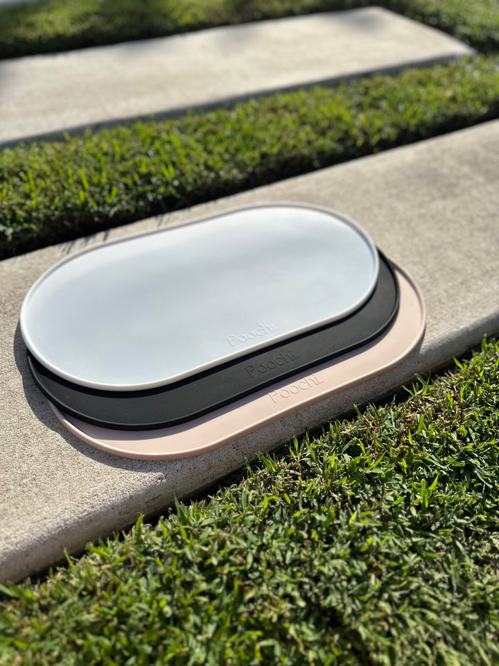 A stack of silicone feeding mats for pets such as dogs or cats. The mat comes in three colours such as black, white and beige